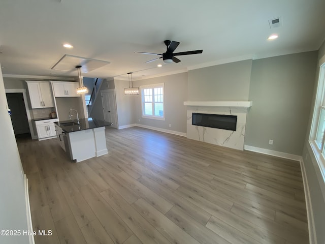 kitchen with dark countertops, a sink, white cabinetry, baseboards, and visible vents