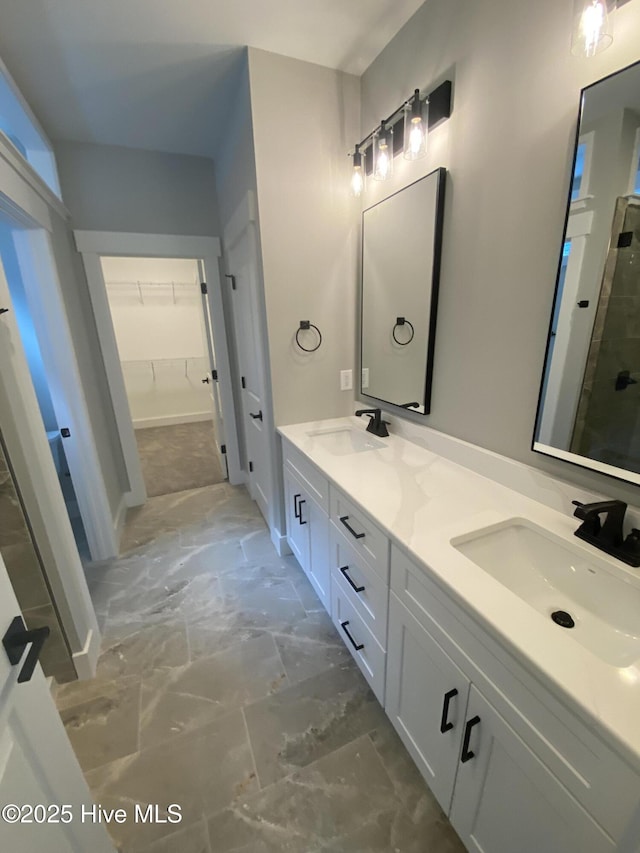full bathroom with double vanity, a spacious closet, a sink, and a stall shower