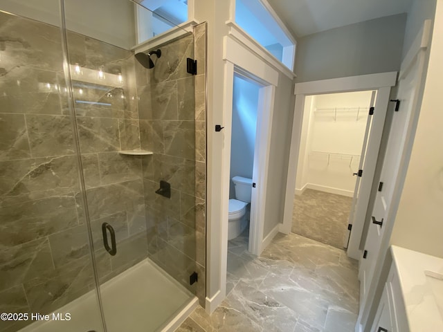 bathroom featuring a shower stall, baseboards, toilet, marble finish floor, and a spacious closet