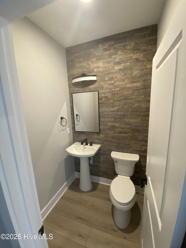 bathroom with baseboards, wood finished floors, and toilet