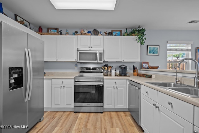 1164 Amber Pines Dr, Leland, NC 28451 - kitchen featuring stainless steel appliances, visible vents, a sink, white cabinetry, and light countertops