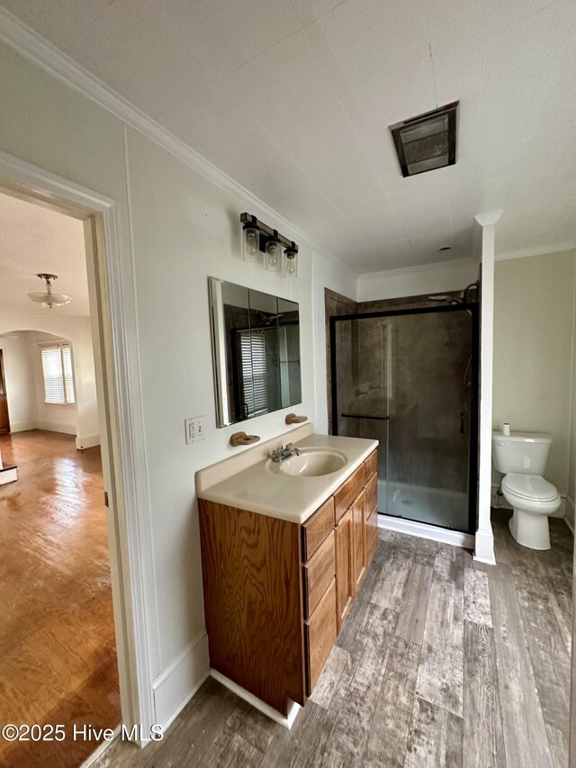 full bath with crown molding, vanity, toilet, wood finished floors, and a stall shower