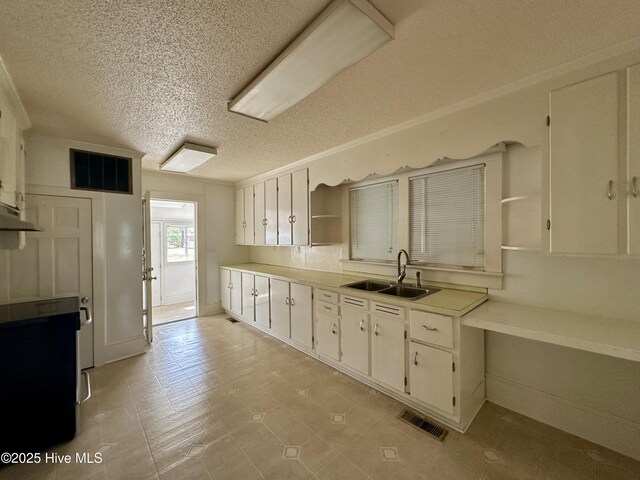 kitchen with a textured ceiling, visible vents, open shelves, a sink, and white cabinets