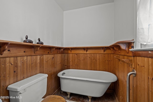 bathroom featuring a freestanding tub, wood walls, wainscoting, and toilet