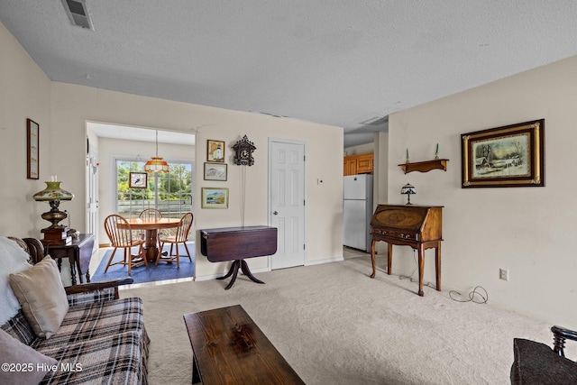 living room featuring visible vents, a textured ceiling, baseboards, and light carpet