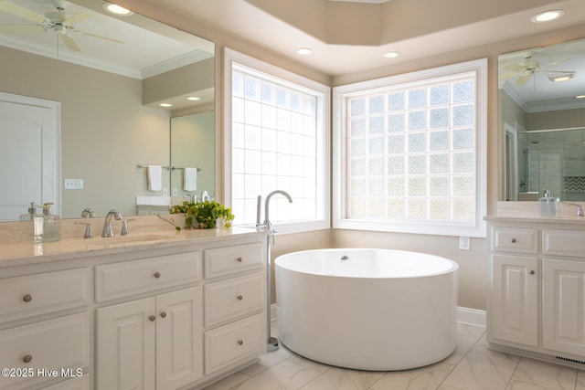 bathroom with a freestanding bath, ornamental molding, a ceiling fan, and two vanities