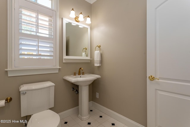 bathroom featuring baseboards, tile patterned floors, and toilet