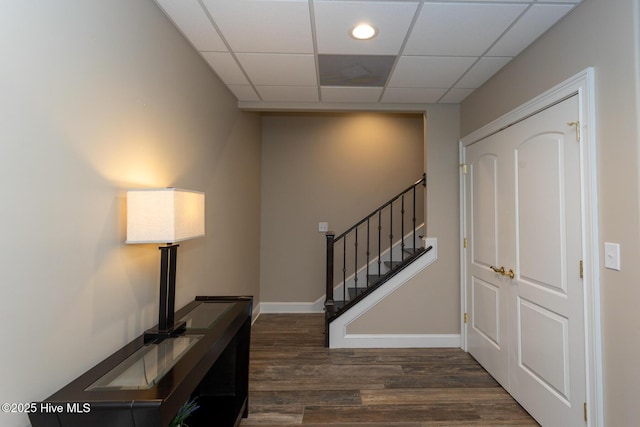 foyer featuring stairs, baseboards, a paneled ceiling, and wood finished floors