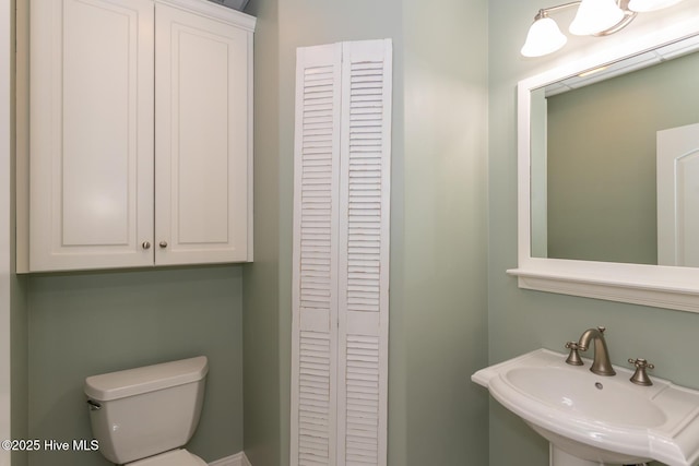 half bath featuring a closet, a sink, and toilet