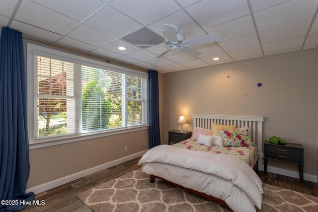 bedroom featuring baseboards, wood finished floors, and a paneled ceiling