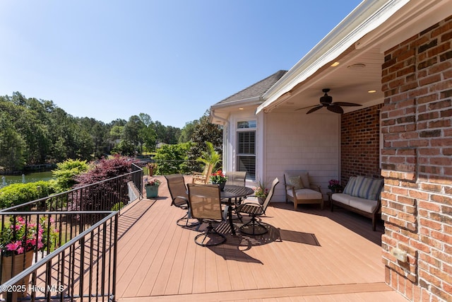 deck featuring a water view, outdoor dining space, and ceiling fan