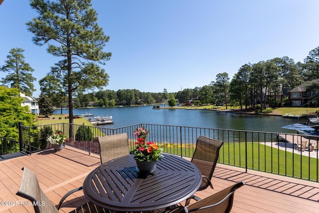 wooden terrace featuring outdoor dining area, a water view, and a yard