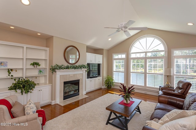 living area with wood finished floors, ceiling fan, recessed lighting, a tile fireplace, and vaulted ceiling