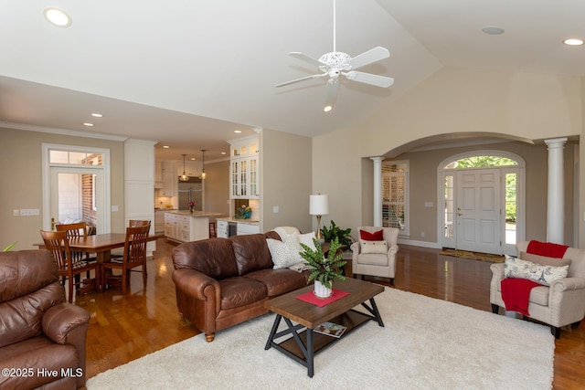 living room featuring arched walkways, ceiling fan, ornate columns, and wood finished floors