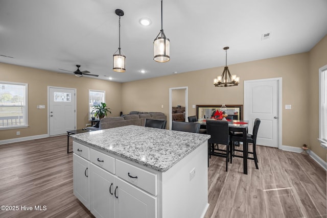 1203 English Colony Pl, Washington, NC 27889 - kitchen with light wood finished floors, a center island, baseboards, white cabinets, and pendant lighting