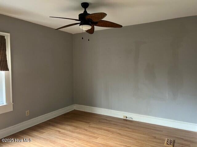 spare room with baseboards, ceiling fan, light wood-type flooring, and visible vents