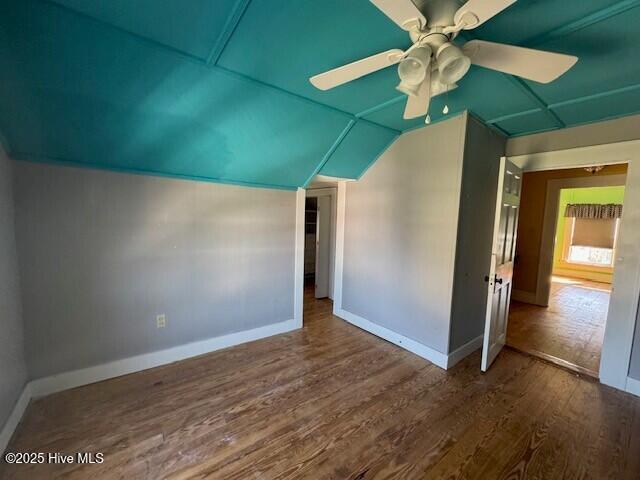 interior space with ceiling fan, baseboards, vaulted ceiling, and wood finished floors