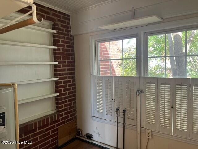 entryway featuring brick wall, plenty of natural light, and ornamental molding