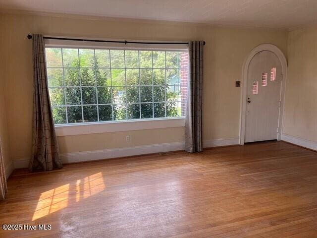 interior space with baseboards, arched walkways, and wood finished floors