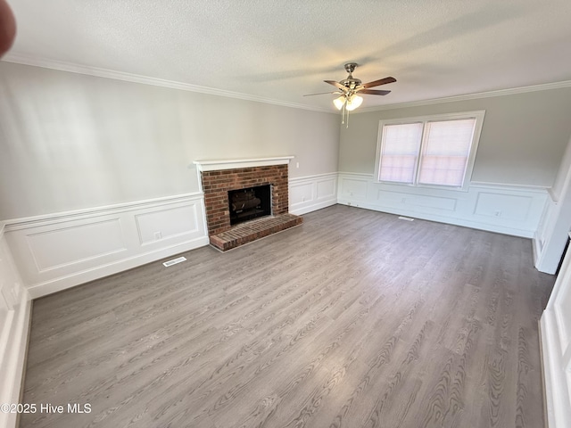 120 Ridgecrest Dr, Mount Olive, NC 28365 - unfurnished living room featuring crown molding, a textured ceiling, a wainscoted wall, a ceiling fan, and wood finished floors