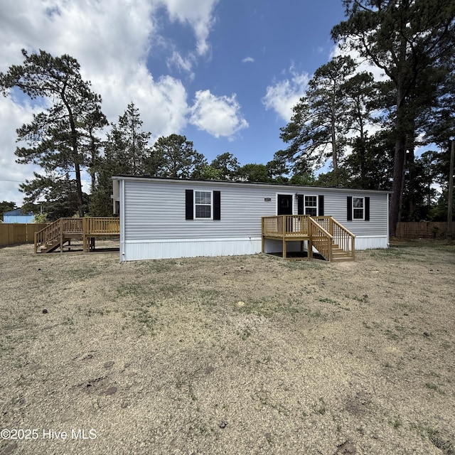 view of front of property featuring a wooden deck, a front lawn, and stairway