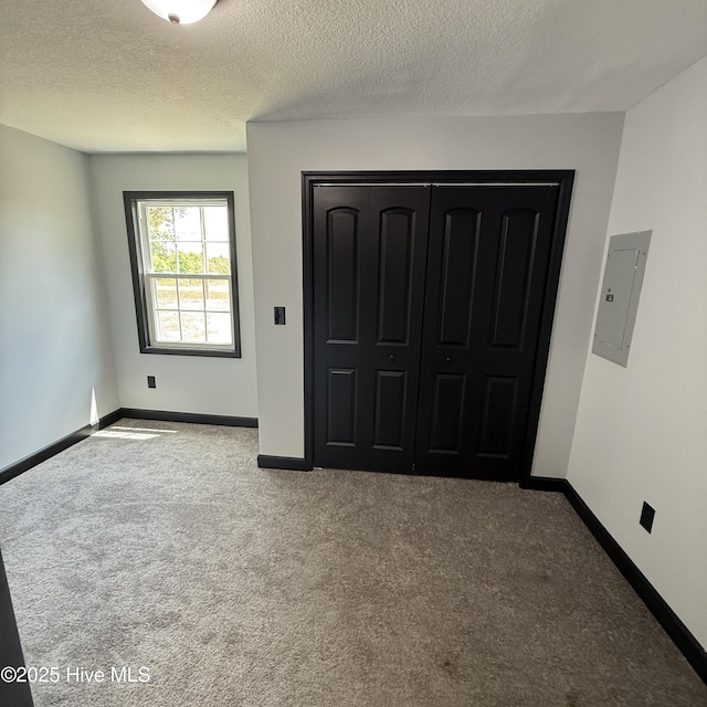 unfurnished bedroom featuring a textured ceiling, baseboards, carpet, and electric panel