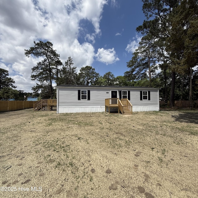 view of front facade with a wooden deck, fence, and a front yard