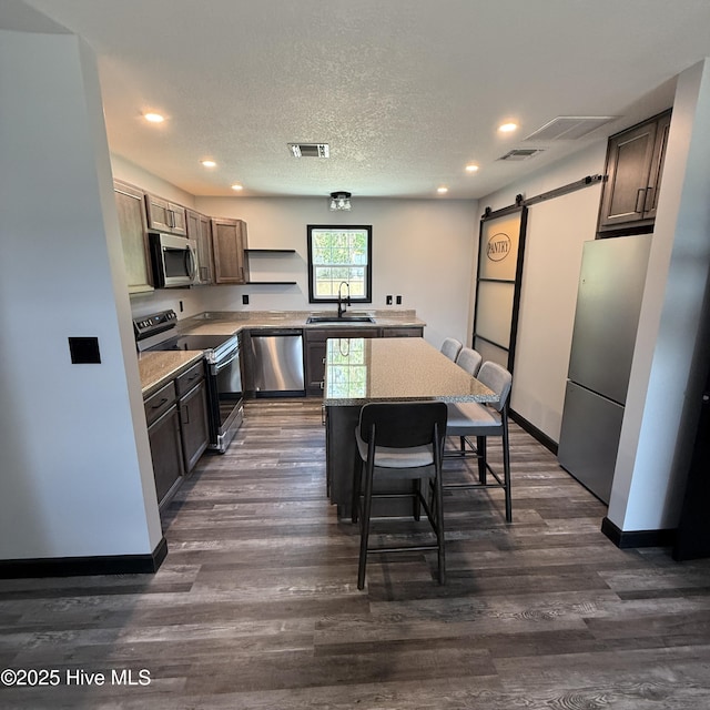 kitchen with recessed lighting, a sink, appliances with stainless steel finishes, and a barn door