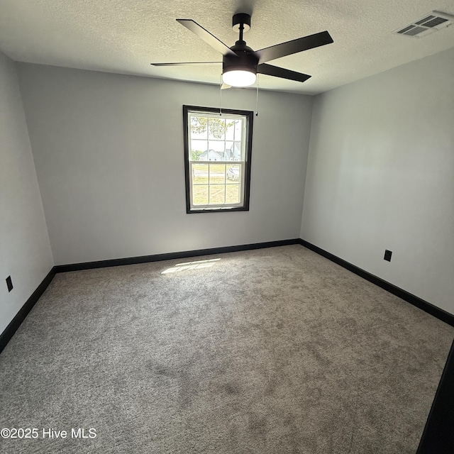 carpeted empty room with visible vents, a textured ceiling, ceiling fan, and baseboards