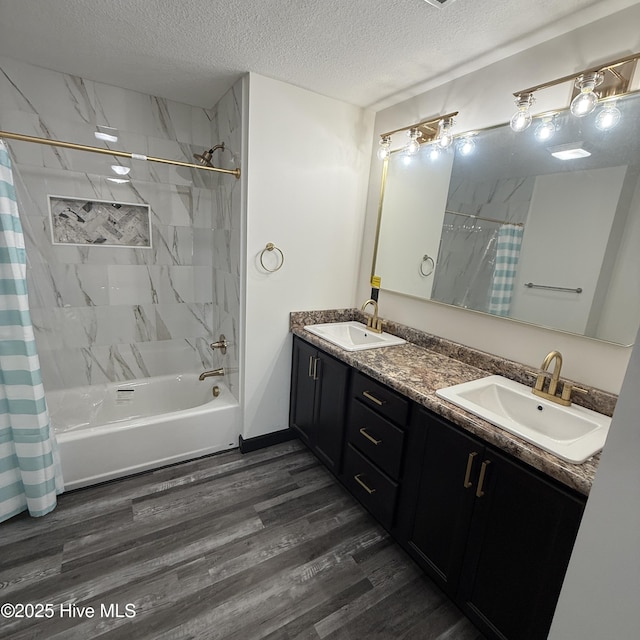 bathroom with a textured ceiling, a sink, shower / bath combo, and wood finished floors