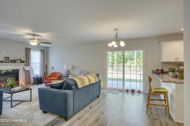 230 Lookout Ln, Sneads Ferry, NC 28460 - living room with a fireplace, light wood finished floors, ceiling fan with notable chandelier, and baseboards