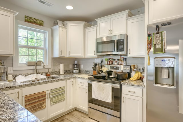 230 Lookout Ln, Sneads Ferry, NC 28460 - kitchen with backsplash, visible vents, white cabinetry, and appliances with stainless steel finishes