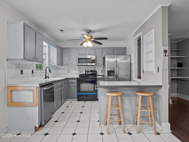 kitchen featuring gray cabinets, visible vents, a sink, a peninsula, and stainless steel appliances