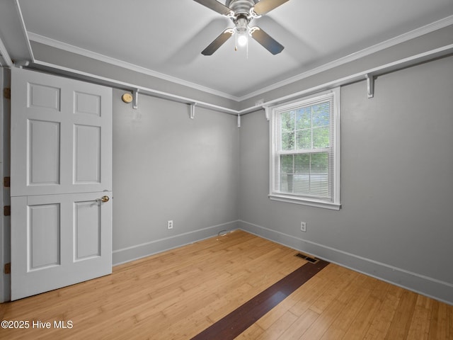 spare room featuring crown molding, ceiling fan, visible vents, and baseboards