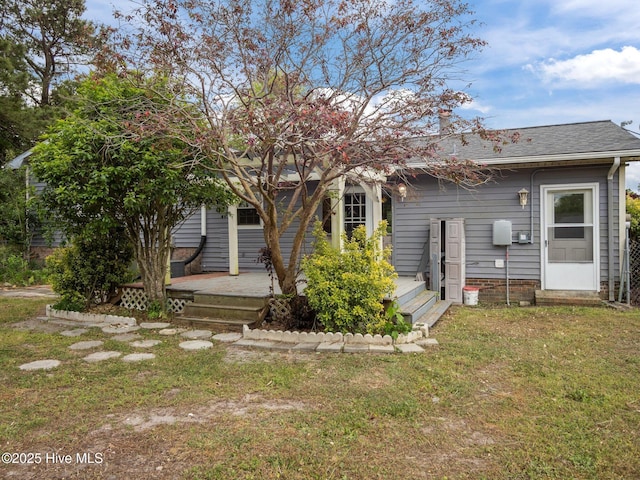 back of house with a yard and a shingled roof