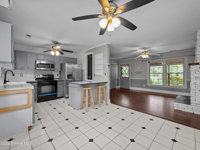 kitchen featuring crown molding, ceiling fan, appliances with stainless steel finishes, a sink, and gray cabinets