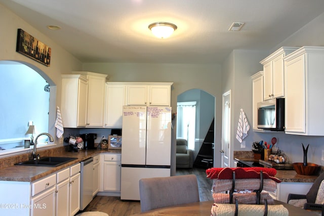 kitchen featuring visible vents, arched walkways, dark countertops, a sink, and stainless steel appliances