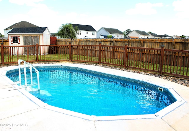 view of swimming pool with an outdoor structure, a fenced in pool, a residential view, and a fenced backyard