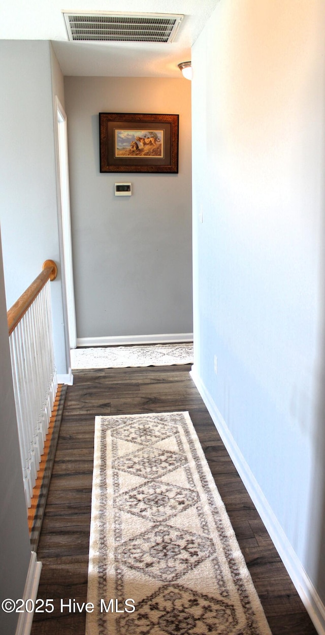 hallway with visible vents, baseboards, and dark wood-style flooring