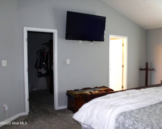carpeted bedroom featuring a closet, a walk in closet, baseboards, and vaulted ceiling