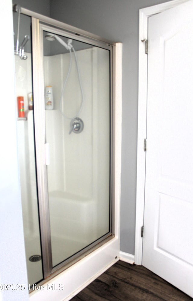 bathroom with wood finished floors and a shower stall