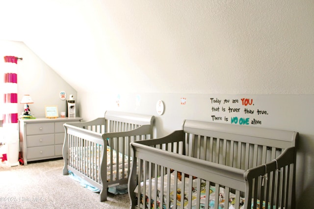 bedroom with light colored carpet, a crib, and lofted ceiling