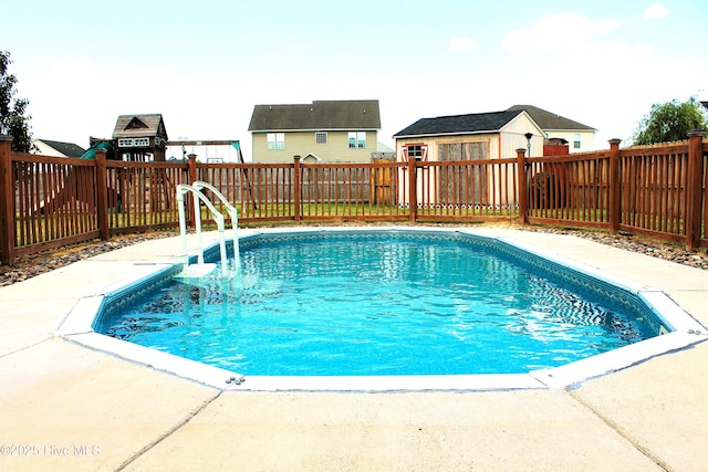 view of swimming pool featuring an outdoor structure, a fenced backyard, a shed, a fenced in pool, and a patio area