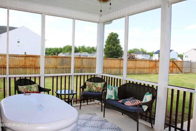 sunroom / solarium with a residential view and ceiling fan