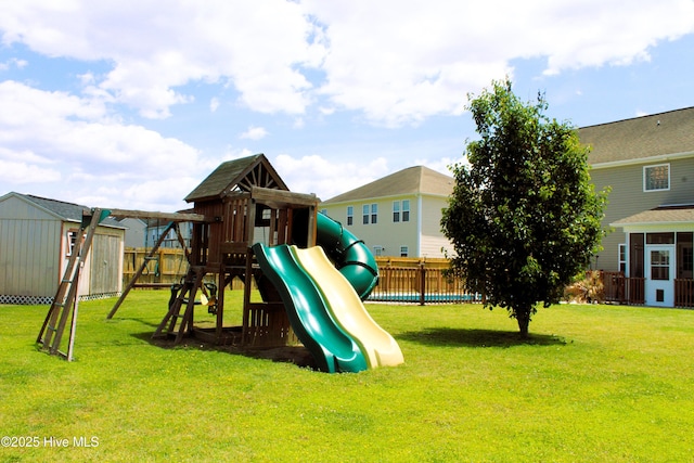 view of play area with fence, a storage unit, and a yard