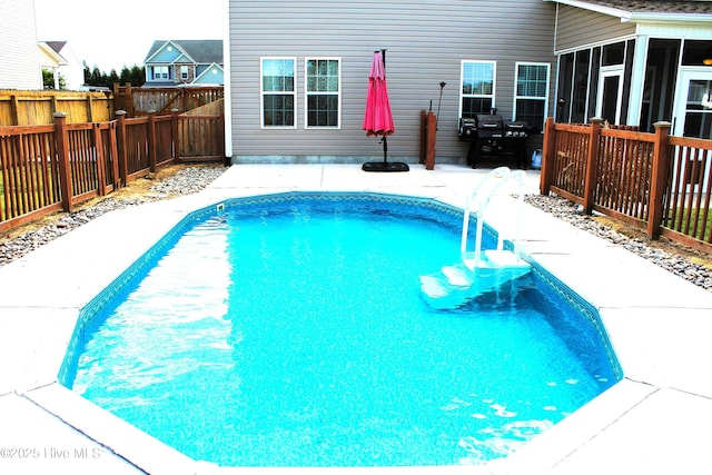 view of swimming pool with a fenced in pool, a sunroom, a fenced backyard, and a patio area