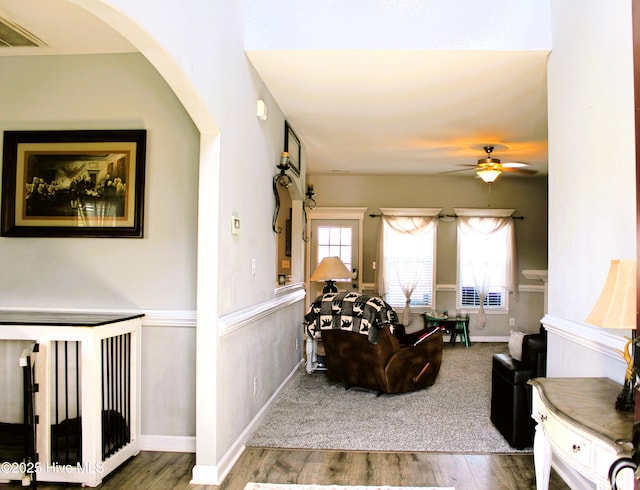 living room with baseboards, a ceiling fan, arched walkways, and wood finished floors