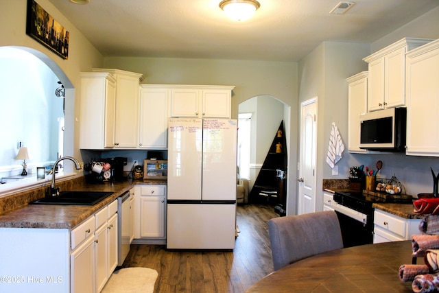 kitchen with visible vents, dark countertops, white appliances, arched walkways, and a sink