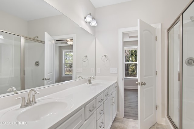 bathroom with a ceiling fan, a stall shower, double vanity, and baseboards