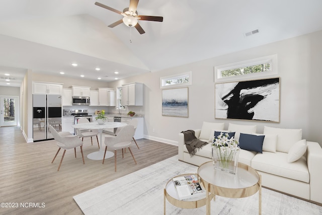 living room with baseboards, light wood-style floors, ceiling fan, vaulted ceiling, and recessed lighting